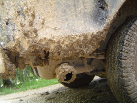 1979 Ford Bronco - Undercarriage and tire heavily coated in mud, obscuring vehicle details.