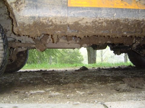 1979 Ford Bronco - Undercarriage of a vehicle heavily coated in mud, with visible rust and damage to the frame.