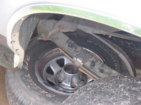1989 Ford Bronco - Close-up view of the rear wheel well and suspension components, including leaf springs and a tire with "Dominator" branding.