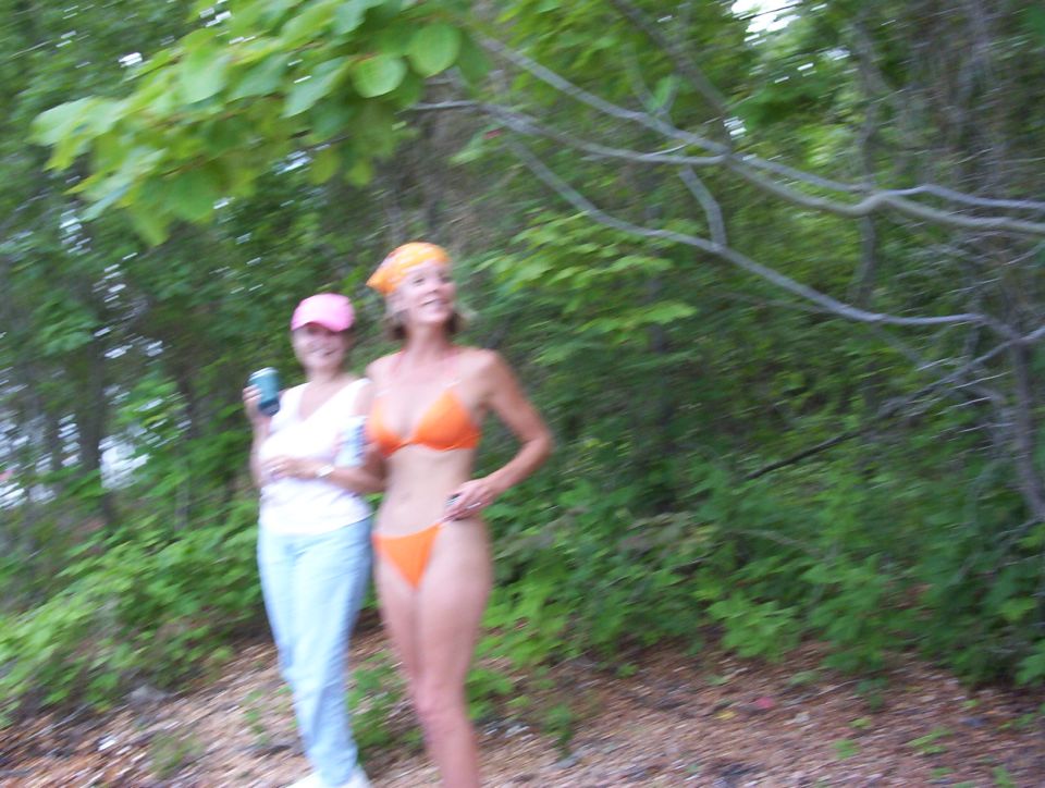 Two women standing on a wooded path, no vehicle shown