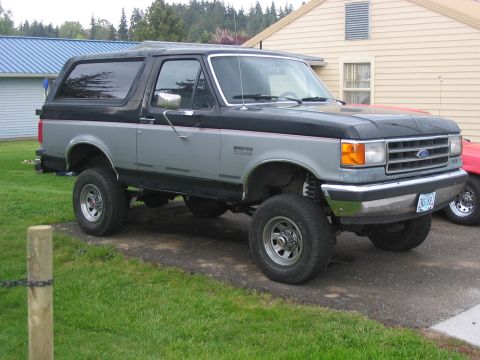 1989 Ford Bronco - This lifted Ford Bronco has a two-tone paint scheme and aftermarket wheels, indicating a modified suspension system.