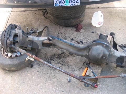 1989 Ford Bronco - A disassembled front axle assembly, likely for a truck or SUV, is shown on the ground.
