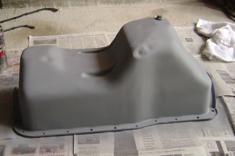 1986 Ford Bronco - A freshly painted oil pan sits on a bed of old newspapers, ready for installation.