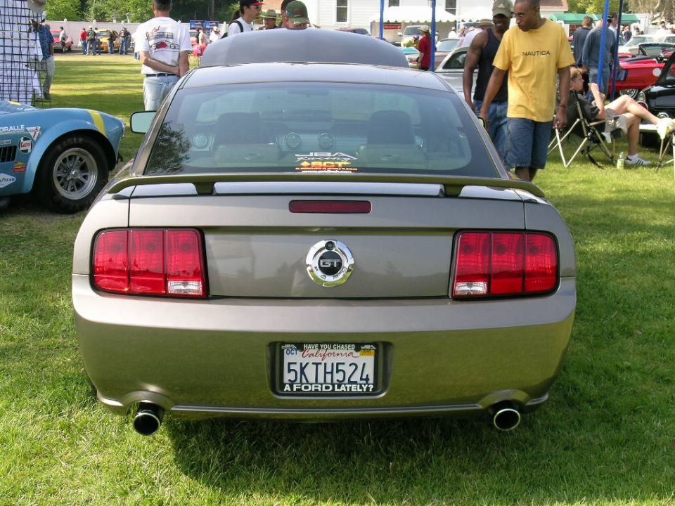 Rear view of a gray Ford Mustang GT with California plate 5KTH524 at a grassy car show