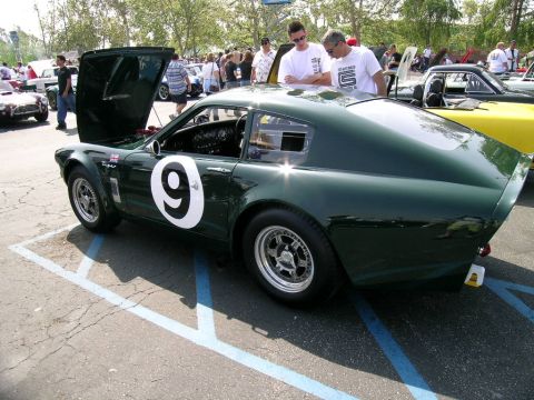 1993 Ford Probe - A dark green race car with a large white number 9 on its side is parked in a lot with other vehicles and spectators.