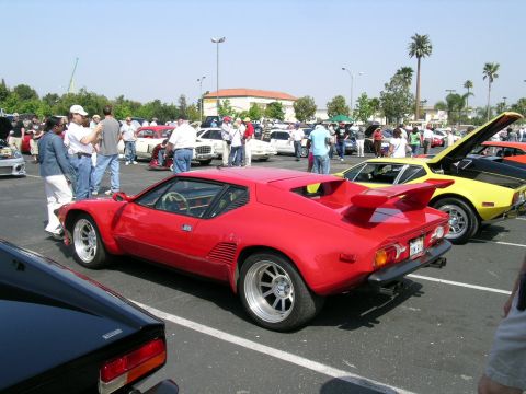 1993 Ford Probe - A red sports car is parked at an outdoor event with other vehicles and people.