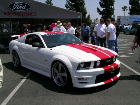 1993 Ford Probe - White Ford Mustang with red racing stripes parked at an outdoor event.