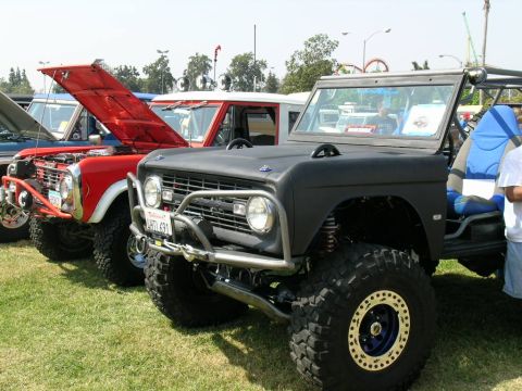 1993 Ford Probe - Several modified Ford Broncos are lined up on a grassy field, with one black Bronco in the foreground.