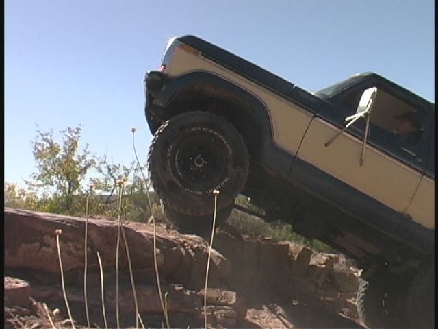 Blue and tan Ford Bronco flexing over rocks off-road with BFGoodrich mud-terrain tires