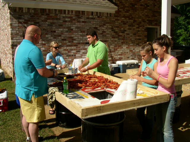 People gathered around a table with crawfish, preparing food outdoors