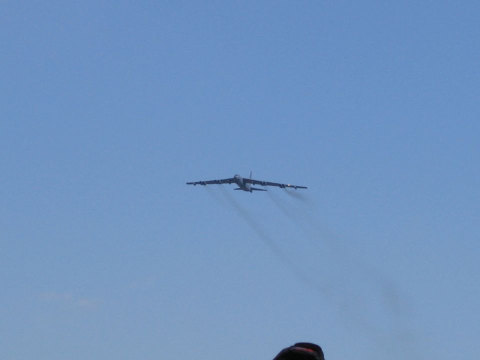 Large multi-engine military jet aircraft flying against a clear blue sky