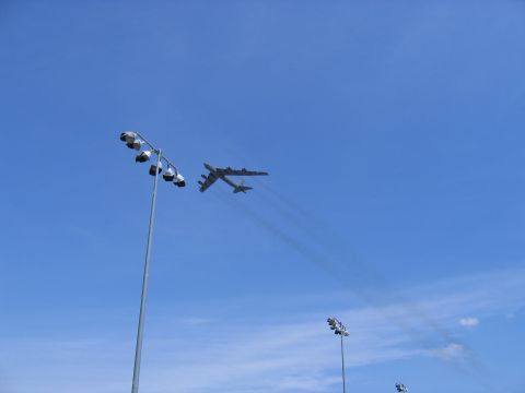2000 Ford Crown Victoria - A B-52 bomber aircraft is seen flying in the sky above stadium lights.
