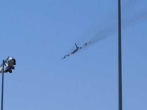 2000 Ford Crown Victoria - An airplane flies overhead, leaving a smoke trail against a clear blue sky.