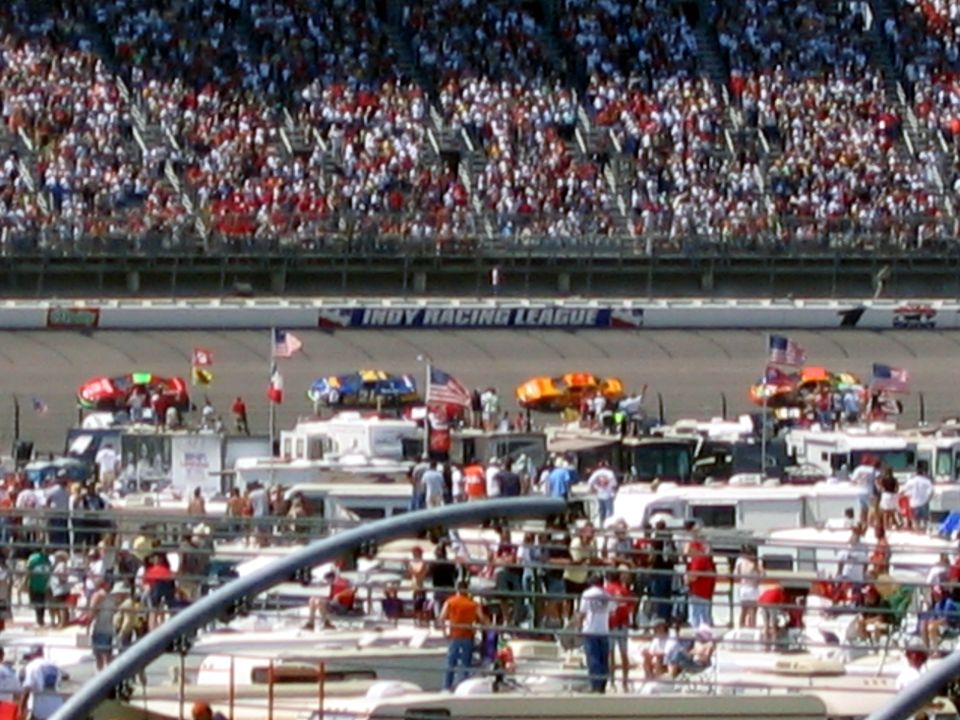 Indy Racing League track with spectators in stands and RVs parked nearby
