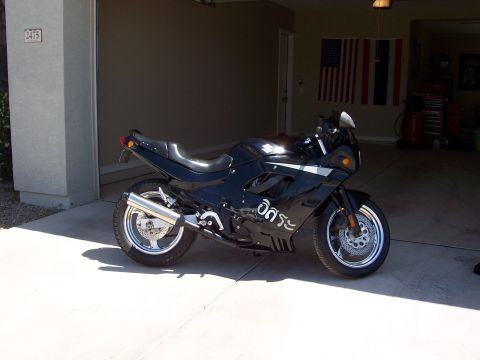 1994 Ford Bronco - Black sport motorcycle with chrome exhaust parked in a garage.