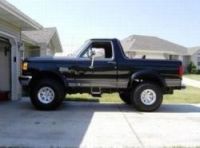 1991 Ford Bronco - Side view of a black Ford Bronco with a lifted suspension and custom wheels.