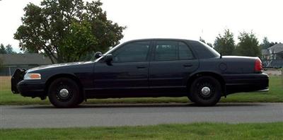 2001 Ford Crown Victoria - A dark 2001 Ford Crown Victoria sedan is parked on the side of the road.