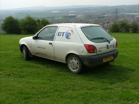 2001 Ford Fiesta - This white Ford van, likely a Fiesta, is parked on a grassy hill with a town in the background.