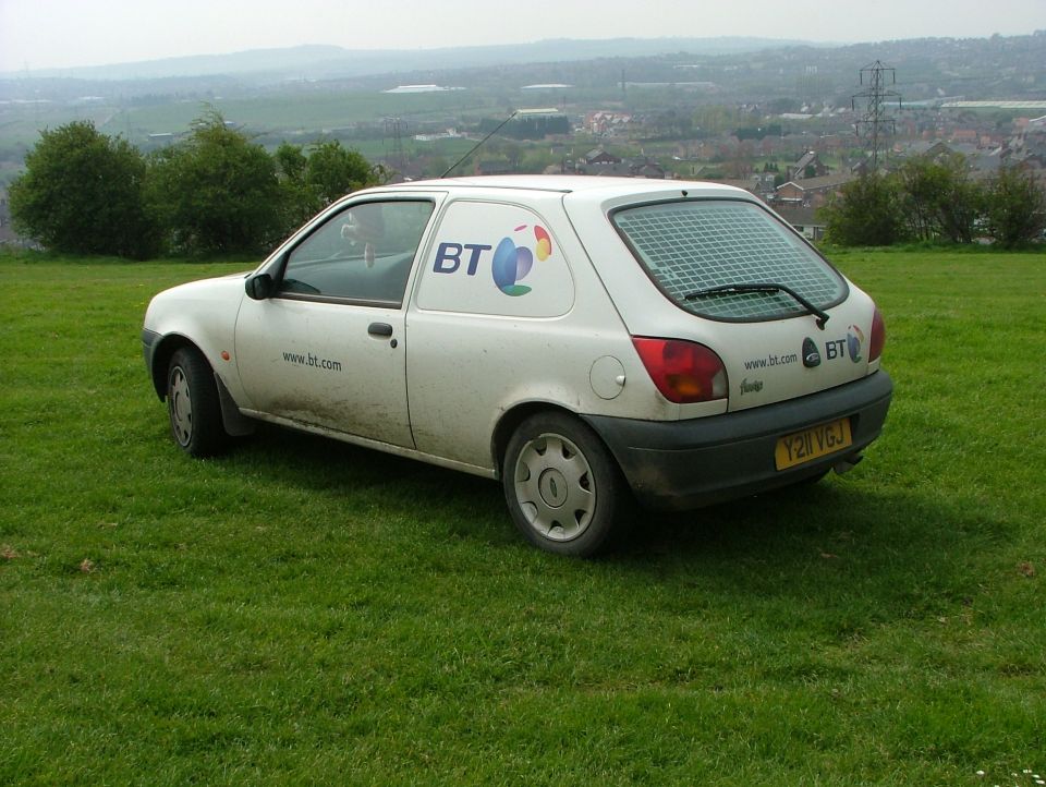 White Ford van with BT logo parked on a grassy hill