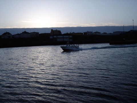 1996 Ford Bronco - A boat travels across the water at dusk, with a town visible on the shore.