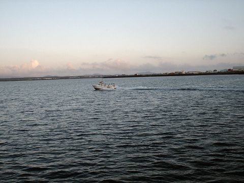 1996 Ford Bronco - A boat travels across the water near a coastal town under a cloudy sky.
