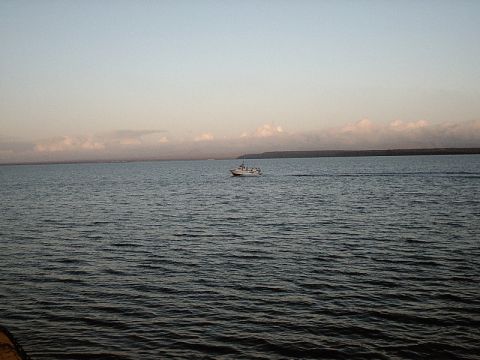 1996 Ford Bronco - A small boat travels across the water under a hazy sky with clouds on the horizon.