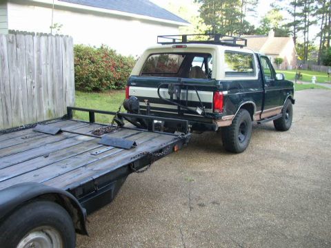 1995 Ford Bronco - This dark green and tan Ford Bronco is equipped with a roof rack and is hitched to a trailer.