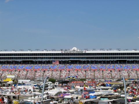 2000 Ford Crown Victoria - A wide view of the Texas Motor Speedway grandstands packed with fans, with a crowded parking area visible below.