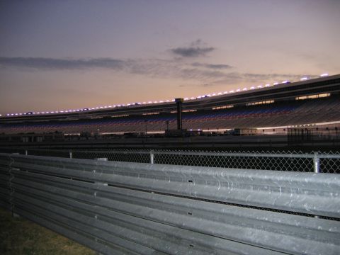 2000 Ford Crown Victoria - Grandstands at Texas Motor Speedway illuminated at dusk, with guardrails visible in the foreground.