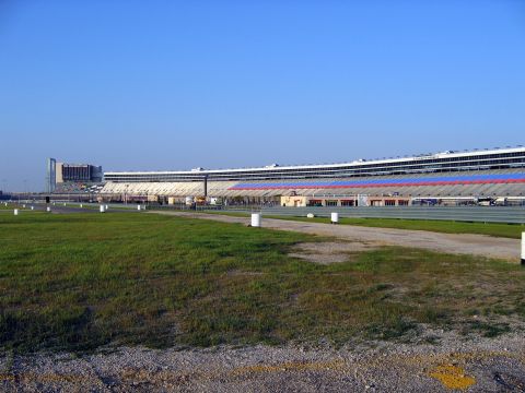 2000 Ford Crown Victoria - The expansive Texas Motor Speedway grandstands and track are visible under a bright blue sky.