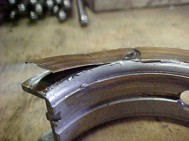 Cracked and chipped curved metal bearing part on a workbench