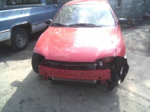 2005 Chevrolet Cavalier - Front view of a red car with significant damage to its front end, parked outdoors.