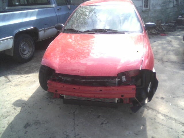 Red car with missing front bumper and grille, parked next to a blue pickup truck