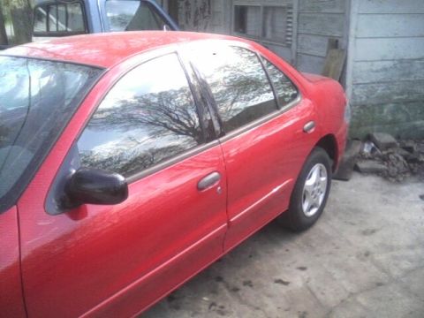 2005 Chevrolet Cavalier - Side view of a red 2005 Chevrolet Cavalier sedan parked next to a building.