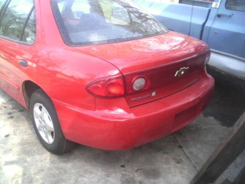 2005 Chevrolet Cavalier - Rear view of a red 2005 Chevrolet Cavalier sedan, parked beside a blue pickup truck.
