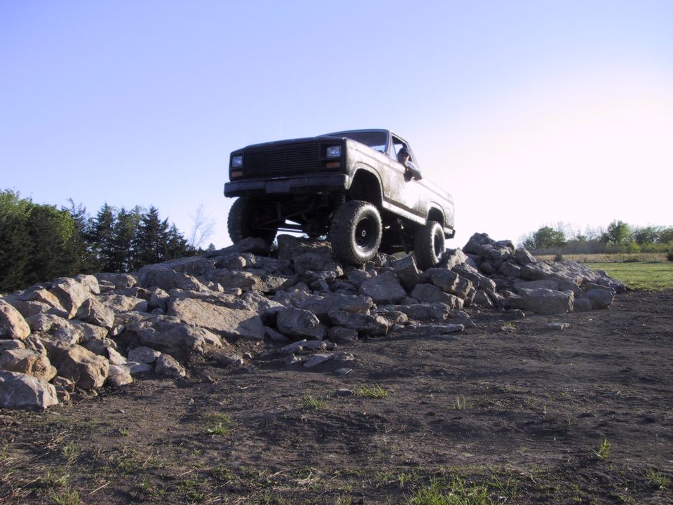 Lifted topless 4x4 crawling over a pile of quarry rock under clear blue sky