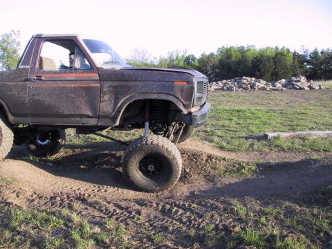 1983 Ford Bronco - This lifted 1980 Ford Bronco is shown off-roading in a grassy, dirt-filled area.