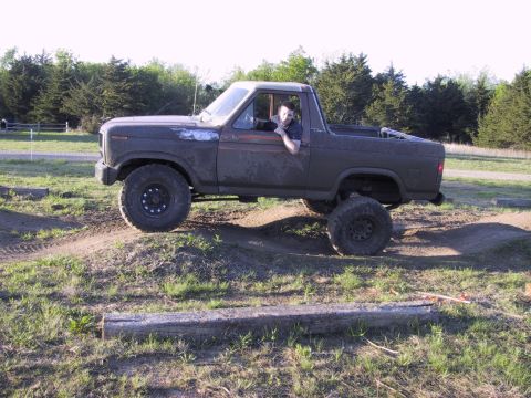 1983 Ford Bronco - Ford Bronco navigates an off-road course with a driver visible inside.