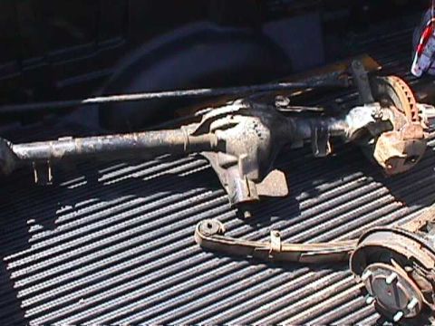 1984 Jeep Wrangler - A rear axle assembly, leaf spring, and brake drum are visible on a ribbed truck bed.