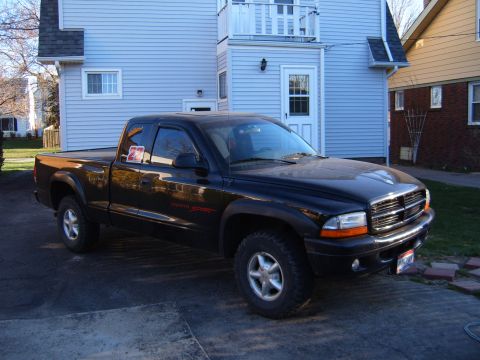 1993 Ford Bronco - A black Dodge Dakota pickup truck is parked in a driveway in front of a house.