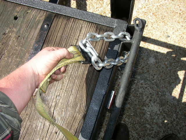 Hand securing strap to trailer chain