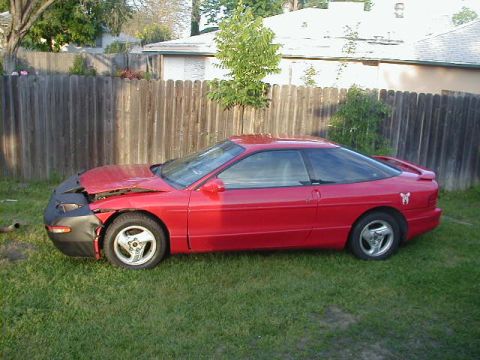 1993 Ford Probe - A red coupe sits on a grassy lawn with its hood open, revealing damage to the front end.