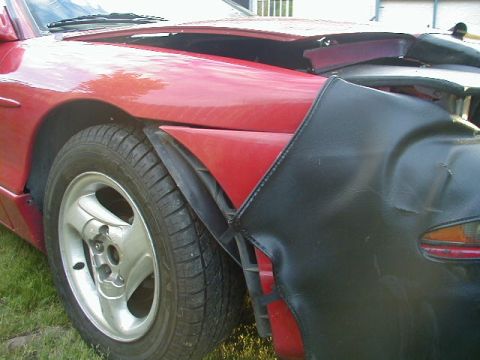 1993 Ford Probe - The front fender and wheel of a red car are visible, with a black cover obscuring part of the front end.