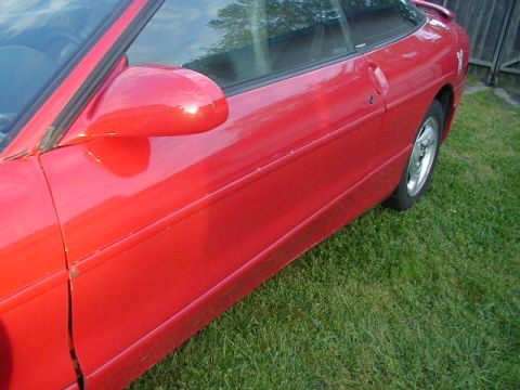 1993 Ford Probe - A red car is parked on grass, with a wooden fence in the background.