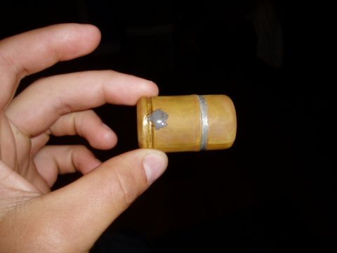 1990 Ford Bronco - A hand holds a small, cylindrical fuel tank cap made of wood with a silver band and a dab of gray sealant.