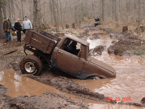 1969 International Scout 800a - A vintage pickup truck is stuck deep in mud while another vehicle navigates the trail behind it.
