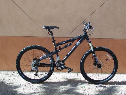 1994 Ford Bronco - A black full-suspension mountain bike is shown parked against a textured wall.