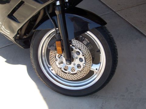1994 Ford Bronco - Close-up of a motorcycle's front wheel assembly, showing the tire, chrome rim, and perforated brake rotor.