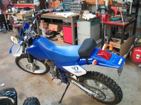 1991 Ford Bronco - A blue Yamaha dirt bike is parked in a workshop, showing its side profile and rear fender details.