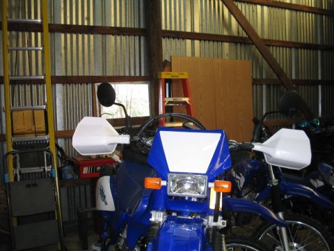 1991 Ford Bronco - Two motorcycles are parked inside a metal-sided structure with ladders and tools nearby.
